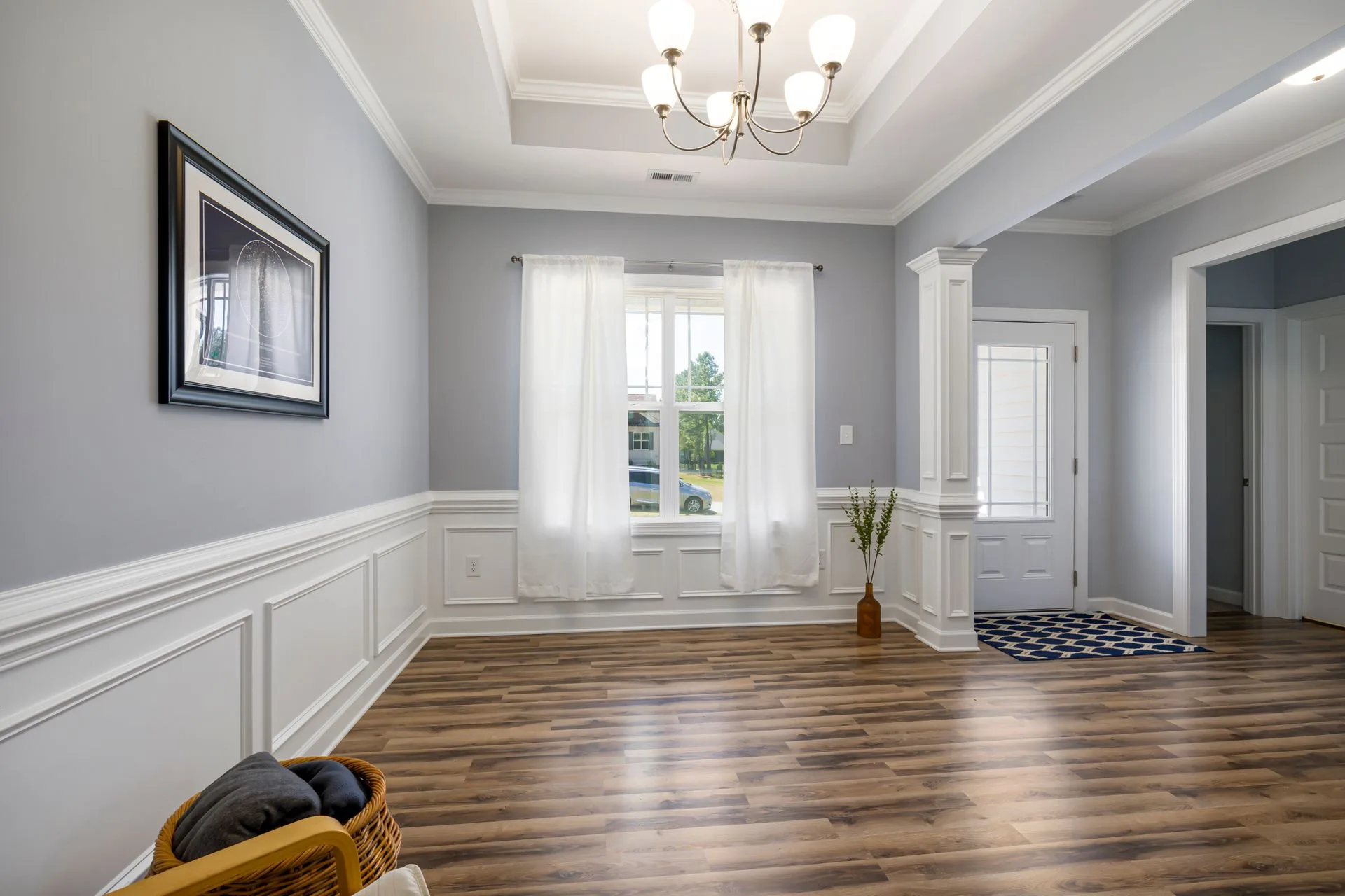 A bright, neutrally staged empty living room with tall windows and natural light