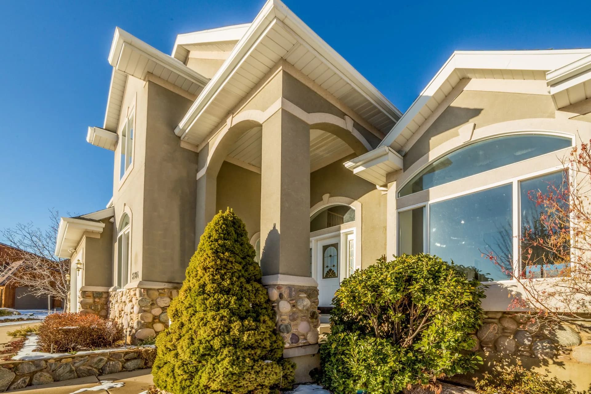 A bright, well-maintained suburban house exterior with a landscaped front yard on a sunny day
